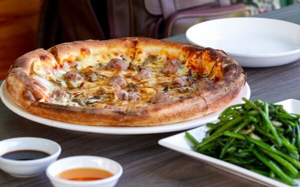 a pizza sitting on A pizza sitting on top of a white plate on top of a wooden table