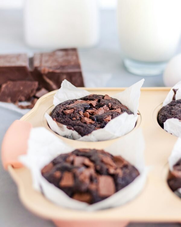 a tray of chocolate a tray of chocolate muffins next to a glass of milk