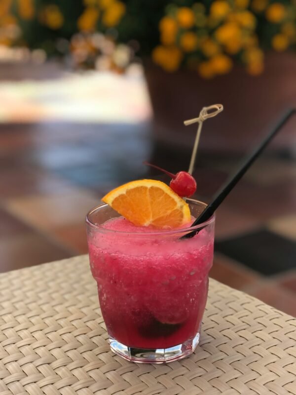 clear drinking glass with clear drinking glass with pink liquid and sliced orange fruit