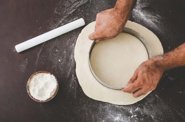 person cutting dough with person cutting dough with round cutter